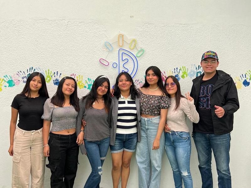 Alumnas frente al muro del logo