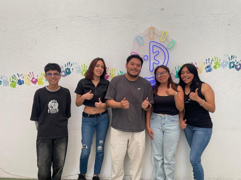 Alumnos celebrando frente al logo de CMUKA